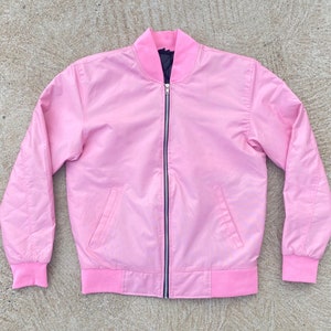 May include: A pink satin bomber jacket with a black zipper and ribbed cuffs and waistband.