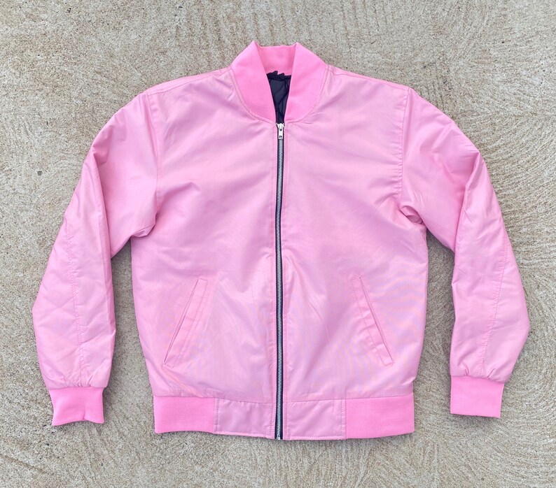 May include: A pink satin bomber jacket with a black zipper and ribbed cuffs and waistband.