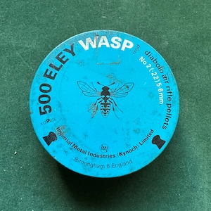May include: A round, light blue tin of 500 ELEY WASP diabolo air rifle pellets. The tin features a wasp illustration and text including "No 2 (.22) 5.6mm" and "Imperial Metal Industries (Kynoch) Limited, Birmingham 6 England."