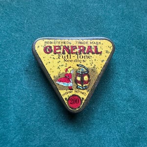 May include: A vintage triangular tin, yellow with red and gold text reading "GENERAL Full-Tone Needles". The tin features illustrations of a girl in a red dress and a spool of thread. It also states "Highly Refined" and "200".
