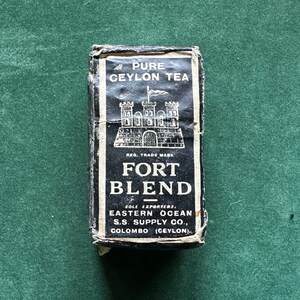 May include: A black and white box with the text "PURE CEYLON TEA" and "FORT BLEND" printed on it. The box also features a black and white illustration of a castle with a flag on top. The text "SOLE EXPORTERS EASTERN OCEAN S.S. SUPPLY CO., COLOMBO (CEYLON)" is printed on the bottom of the box.
