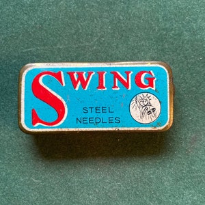 以下が含まれることがあります： 青と白の金属製の缶に、赤い文字で「SWING」、黒い文字で「STEEL NEEDLES」と書かれています。缶には、青いドレスを着た女性が松明を持っている絵が描かれています。