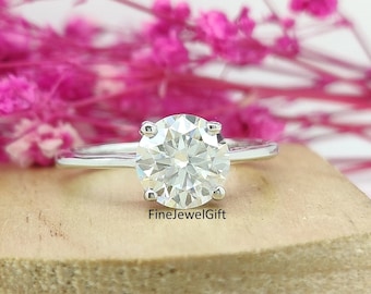 May include: A silver ring with a large, round, clear diamond solitaire.