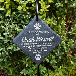 May include: A black slate memorial stone with a white paw print design and the text "In Loving Memory of Onah Wescott. A small dog with a huge heart, who will be forever missed. You left before we were ready to say goodbye."