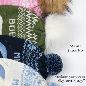 Puede incluir: Cuatro gorros de punto con patrones de copos de nieve y nombres. El gorro superior tiene un pomp&oacute;n de piel sint&eacute;tica de mapache rojo, el segundo uno de piel sint&eacute;tica blanca, el tercero uno de lana mediano de 6,5 cm y el inferior uno peque&ntilde;o de 4,5 cm.
