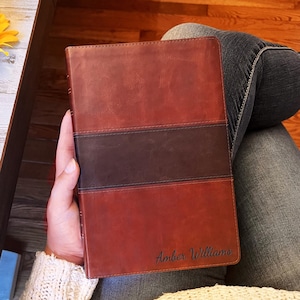 May include: A brown leather journal with a dark brown band and the name "Amber Williams" embossed on the front.