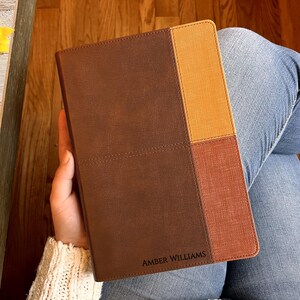 May include: A brown leather-bound journal with a stitched design. The cover is divided into three sections: brown, yellow, and orange. The journal is personalized with the name "Amber Williams".