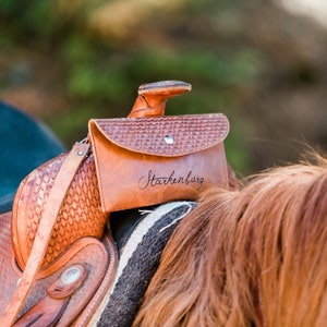 K&ouml;nnte beinhalten: Ein brauner Ledersattel mit einer braunen Ledertasche. Die Tasche tr&auml;gt die Aufschrift "Starkenburg".