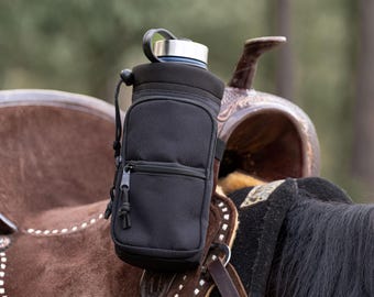 May include: Black water bottle holder with a zippered pocket, attached to a brown leather saddle. The holder has a silver-colored lid and a black strap. The saddle is decorated with white stitching.