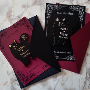 May include: Two wedding invitation cards with black cat designs. One card is black with white text and a black cat silhouette. The other card is burgundy with a black cat design and gold text. Both cards say "Save the date" and include names and dates.