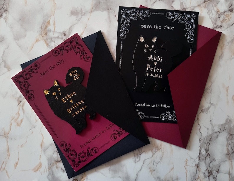 May include: Two wedding invitation cards with black cat designs. One card is black with white text and a black cat silhouette. The other card is burgundy with a black cat design and gold text. Both cards say "Save the date" and include names and dates.