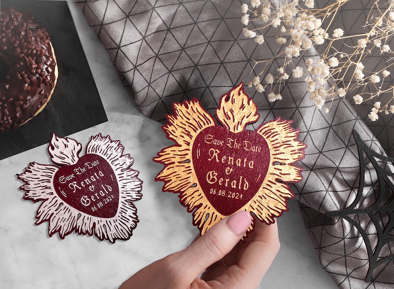 K&ouml;nnte beinhalten: Zwei rote herzf&ouml;rmige Save-the-Date-Karten mit goldenen Akzenten. Der Text auf den Karten lautet "Save the Date Renata & Gerald 06.08.2024".