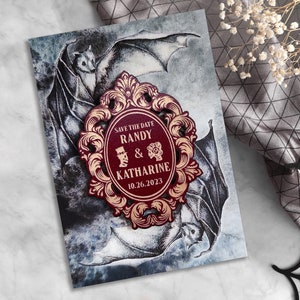 Puede incluir: Tarjeta de guardar la fecha con un marco adornado en color burdeos y dorado con el texto "Save the Date Randy & Katharine 10.26.2023" y una ilustraci&oacute;n en blanco y negro de murci&eacute;lagos.