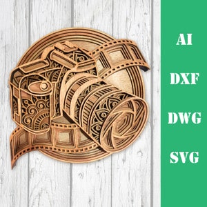 Pode incluir: Uma pe&ccedil;a de arte em madeira em camadas que retrata uma c&acirc;mera com uma tira de filme, mostrando padr&otilde;es e designs intrincados. A obra de arte &eacute; em tons de marrom e bege, com o texto "AI, DXF, DWG, SVG" em branco sobre um fundo verde.