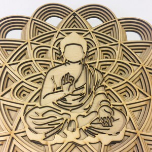 May include: A wooden wall hanging featuring a detailed laser-cut design of a meditating Buddha figure sitting in the center of a mandala pattern.