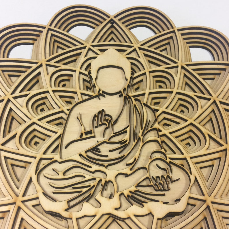 May include: A wooden wall hanging featuring a detailed laser-cut design of a meditating Buddha figure sitting in the center of a mandala pattern.