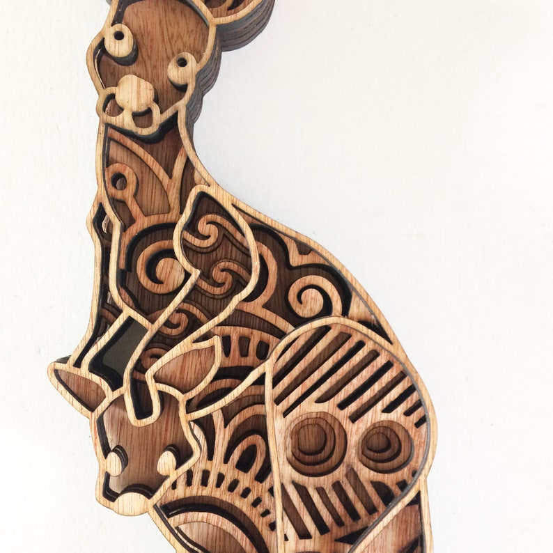 May include: A wooden wall art sculpture of a kangaroo with intricate laser-cut designs. The kangaroo is brown and has a detailed pattern of swirls and lines.