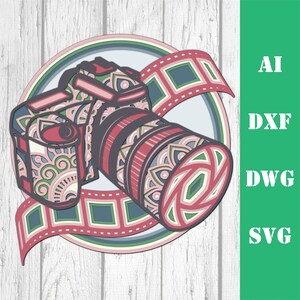 Pode incluir: Um design de arte em papel em camadas de uma c&acirc;mera com uma lente, uma tira de filme e um fundo circular. A c&acirc;mera e a tira de filme s&atilde;o em tons de rosa, verde e cinza. O texto "AI, DXF, DWG, SVG" est&aacute; &agrave; direita.