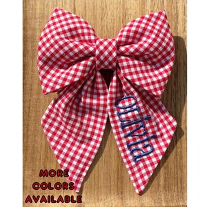 May include: Red and white gingham bow with the name "Olivia" embroidered in blue thread.