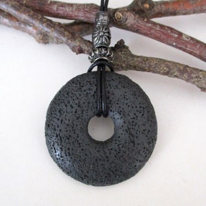 May include: A black lava rock donut pendant necklace with a silver metal clasp and black leather cord.