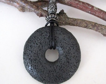 May include: A black lava rock donut pendant necklace with a silver metal clasp and black leather cord.