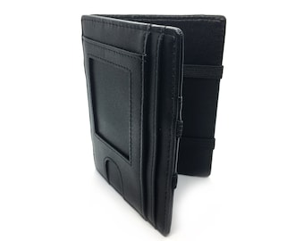 Op de afbeelding: Een zwarte lederen bifold portemonnee met een transparant ID-venster aan de voorzijde, meerdere verticale kaartsleuven en een zwarte elastische band aan de zijkant om de portemonnee in gesloten toestand bij elkaar te houden.