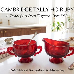 Può includere: Set di cristalleria Cambridge Tally Ho Ruby composto da una zuccheriera a due manici e una salsiera in vetro rosso intenso con dettagli a coste orizzontali e basi a piedistallo. Testo: CAMBRIDGE TALLY HO RUBY. A Taste of Art Deco Elegance, Circa 1930.