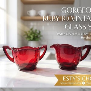May include: A pair of vintage ruby red glass vessels, including a sugar bowl with two handles and a creamer with a spout and single handle, featuring the Paden City Crow's Foot pattern. Each piece measures 7.5 cm in height.