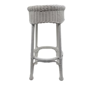 May include: White wicker bar stool with a round seat and four legs. The stool is made of woven wicker and has a white finish.