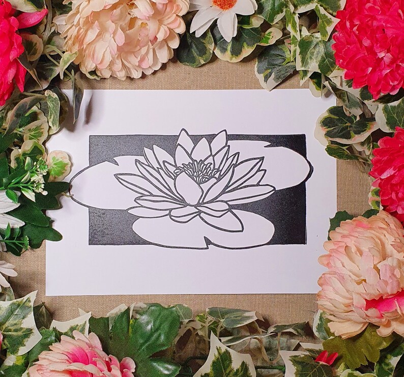 May include: A black and white line drawing of a water lily on a white background. The water lily is in the center of the image and is surrounded by a black border.