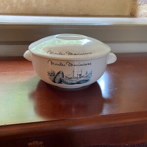 以下が含まれることがあります： 白地に青と白の貝と船の絵が描かれた白い陶器のボウル。ボウルには蓋が付いており、側面には「Moules Bouillonneves」の文字が書かれている。
