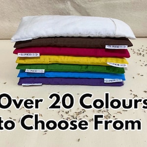 May include: A stack of seven eye pillows in various colors, including white, brown, red, yellow, green, blue, and purple. The text "Over 20 Colours to Choose From" is printed below the pillows.