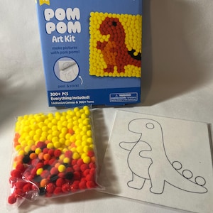 May include: A Pom Pom Art Kit in a blue box featuring a dinosaur design, a clear plastic bag filled with yellow, red, and black pom poms, and a square white adhesive canvas with a black outline drawing of a dinosaur for crafting projects.