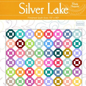 May include: A colorful quilt with a geometric pattern of octagons in various colors, including green, blue, pink, and orange. The quilt is labeled "Silver Lake" and measures 72" x 90". The design is by Wendy Sheppard.