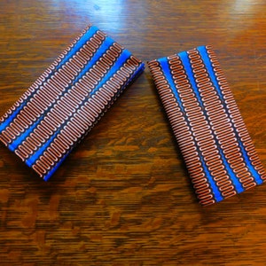 Può includere: Due quadrati di tessuto con un motivo ripetitivo di ovali arancioni e bianchi su sfondo blu.