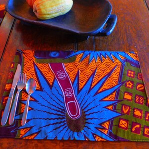 Puede incluir: Un mantel individual azul y naranja con un patrón geométrico y un juego de cubiertos encima. El mantel individual está sobre una mesa de madera.