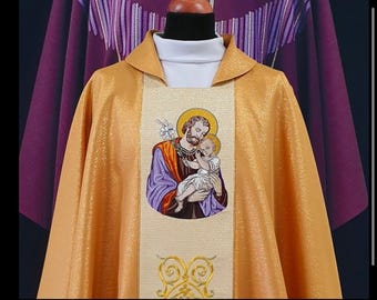 May include: A gold liturgical vestment with an embroidered image of Saint Joseph holding the baby Jesus. The vestment has a purple trim and a white collar.