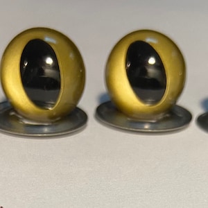 May include: Four gold plastic safety eyes with black pupils, each mounted on a silver washer.