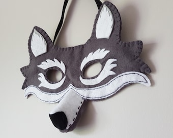 May include: Grey felt wolf mask with white felt accents and a black felt nose. The mask has eye holes and a felt strap for wearing.