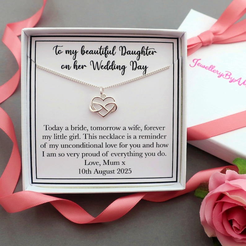 May include: A white gift box with a silver necklace inside. The necklace features a heart with an infinity symbol. The box has a message that reads "To my beautiful Daughter on her Wedding Day. Today a bride, tomorrow a wife, forever my little girl. This necklace is a reminder of my unconditional love for you and how I am so very proud of everything you do. Love, Mum x 10th August 2025."