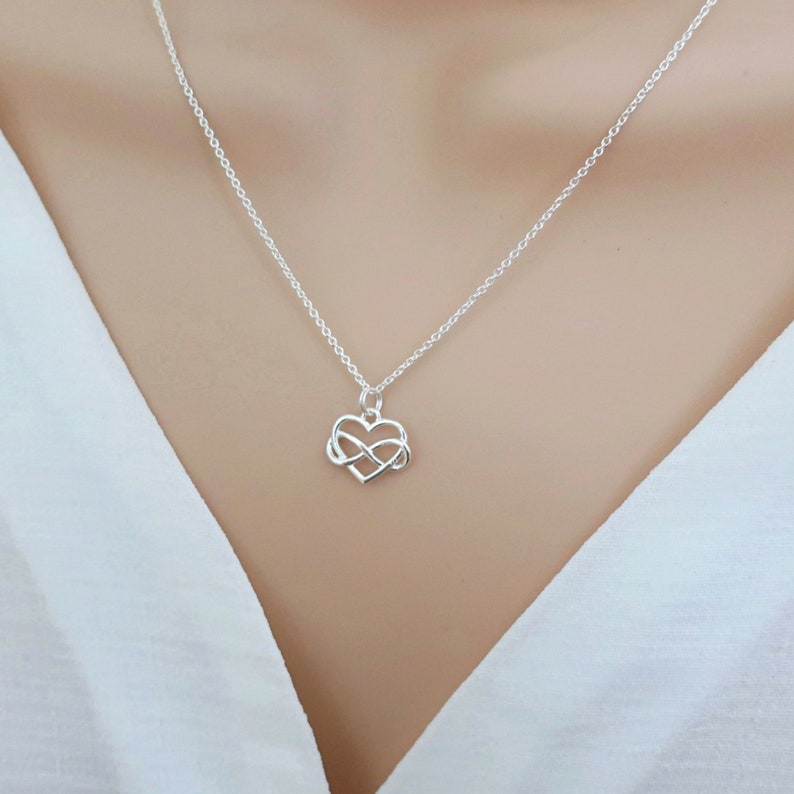 May include: A silver necklace with a heart-shaped pendant featuring an infinity symbol. The necklace is delicate and simple, making it a perfect gift for a loved one.