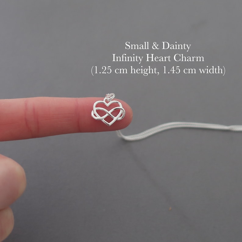 May include: A silver infinity heart charm pendant on a silver chain. The charm is 1.25 inches tall and 1.45 inches wide.