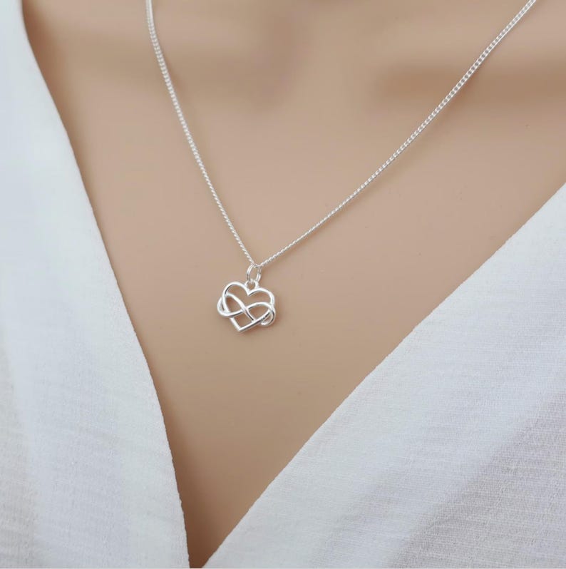 May include: A silver necklace with an infinity symbol heart pendant.