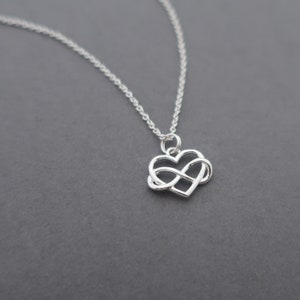 May include: A silver necklace with an infinity symbol pendant in the shape of a heart.