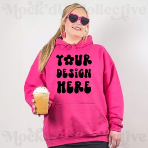 May include: A bright pink hoodie with a black graphic that says "YOUR DESIGN HERE" in a retro font. The hoodie has a drawstring hood and a kangaroo pocket.
