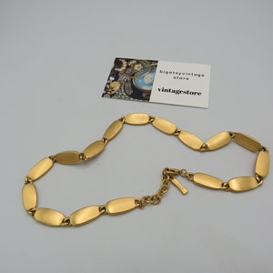 May include: A gold-toned necklace with a chain made of oval-shaped links. The necklace has a clasp closure.
