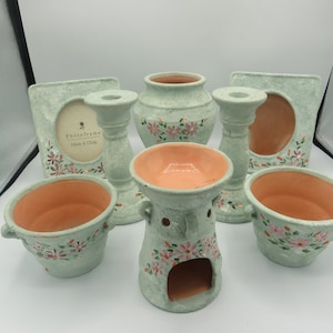 May include: Set of six green ceramic items with floral designs. Includes two candle holders, a vase, a photo frame, and two small bowls. The photo frame has the text "Photoframe 11cm x 13cm".