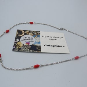 May include: A silver chain necklace with red oval beads. The necklace is on a white background. The text on the card reads "Find me on Instagram vintage_etsystore" and "bigetsyvintage store" and "vintagestore".