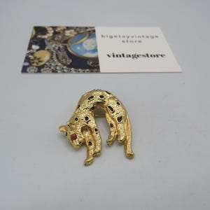 stunning vintage gold tone cat/leopard brooch with a rhinestone bail to be used as a pendant, black enamel detailing, red eye, 4cm length