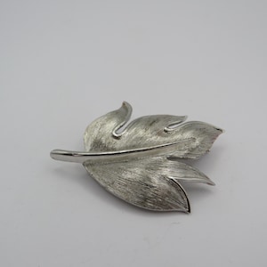 May include: A set of three ceramic mugs with a speckled, matte finish. The mugs are in shades of cream, light gray, and dark gray. Each mug has a simple, minimalist design, perfect for coffee or tea.